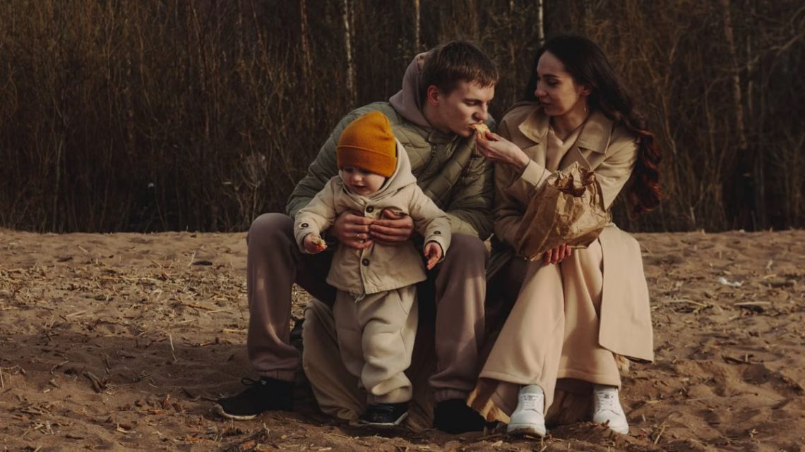 A family enjoys a cozy moment outdoors with their child during autumn. Warm and intimate scene.